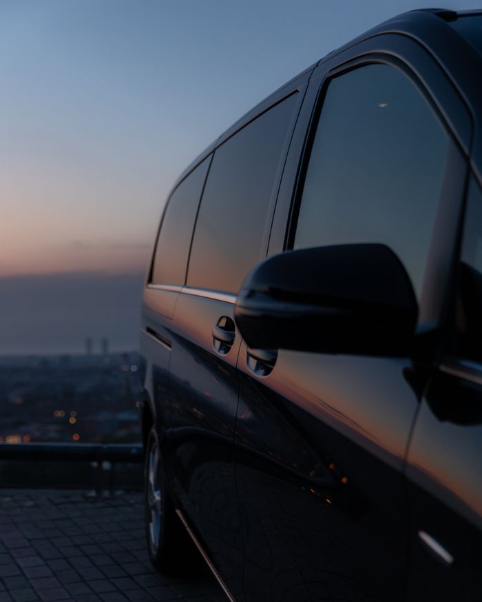 The Art of Drawing Readers In: Your attractive post title goes here A luxury black car with tinted windows parked at a city overlook during dusk, reflecting twilight hues.